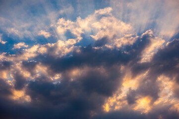 Dramatic sunset sky with sun rays through clouds.