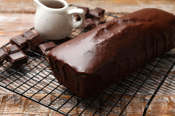 Tasty sponge cake and pieces of chocolate on wooden table, closeup