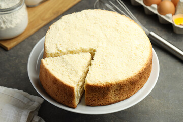 Tasty cut sponge cake on grey table