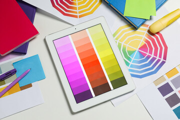 Designer's workplace with tablet, different palettes and stationery on white table, flat lay