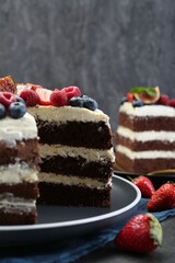 Delicious chocolate sponge cake with berries on table, closeup