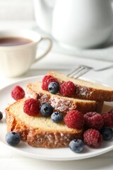 Freshly baked sponge cake, raspberries and blueberries on white wooden table, closeup