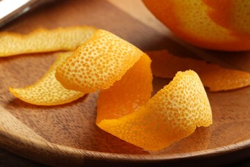 Fresh orange peel and fruit on wooden table, closeup