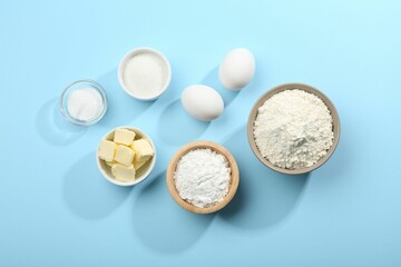 Baking powder and other ingredients for making dough on light blue background, flat lay