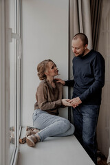 Couple man and woman holding hand on windowsill at home