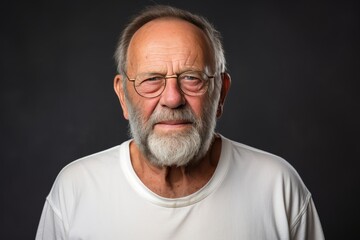 Obraz premium Joyful elderly man in white t shirt poses happily in studio against solid backdrop