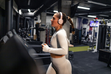 Female athlete running on treadmill and training in the gym.