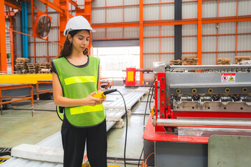 Smart female mechanical engineer is using a remote control to operate a crane or robot in a metal sheet factory. Female expert technical worker is using remote controller to control machine.