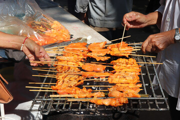 Thai-style grilled pork, Thai street food.person hand-choosing pork grilled for eating.