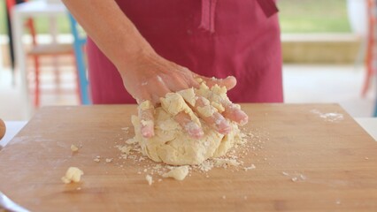 A person is seen kneading dough on a wooden surface, skillfully preparing for baking. This closeup captures the hands mixing various ingredients for making delicious pastry or bread