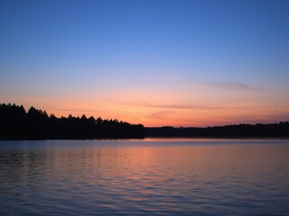 peaceful lake at dusk with silhouetted trees, gentle evening light, serene mood, silhouetted trees