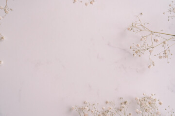 Elegant Floral Frame Border with White floral branch on  white marble background. Invitation, greeting card. Copy space, mock up template. Flat lay, top view, minimal composition.