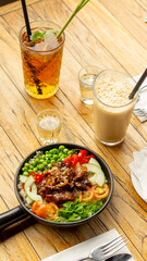 Beef Black Pepper Poke Bowl served on the table with Cappuccino and Iced Tea