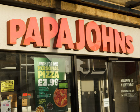 Sign and logo  over entrance to multi national pizza and fast food restaurant Papa Johns who also provide a takeaway and delivery service of their meals