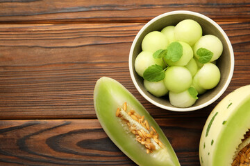 Melon balls in bowl and fresh fruit on wooden table, flat lay. Space for text