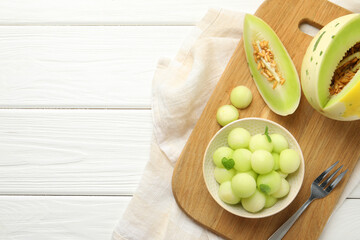 Melon balls in bowl and fresh fruit on white wooden table, top view. Space for text