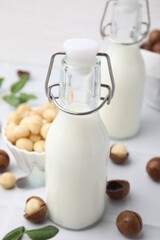 Bottles of macadamia milk and nuts on white tiled table
