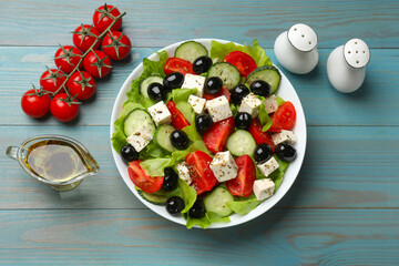 Delicious salad with feta cheese served on light blue wooden table, flat lay