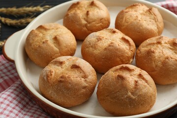 Baking dish with homemade tasty buns on table, closeup