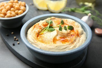 Delicious hummus with paprika and chickpeas served on dark grey table, closeup