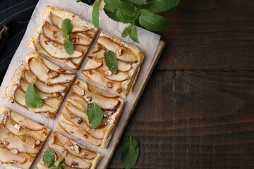 Tasty puff pastry pie with pears and mint on wooden table, top view. Space for text