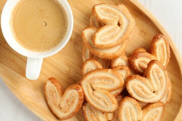 Delicious palmier cookies with coffee on white wooden table, top view