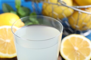 Fresh juice in glass and lemons on table, closeup