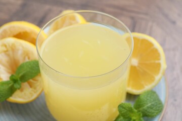 Glass of lemon juice and fresh fruits on wooden table, closeup