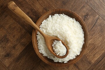 White soy wax flakes in bowl and spoon on wooden table, top view