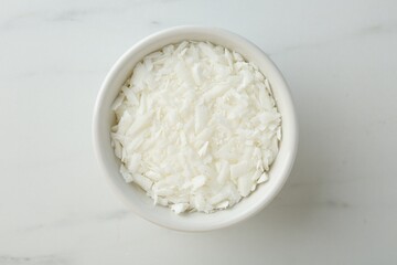 Soy wax in bowl on white marble table, top view