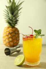 Tasty pineapple cocktail with mint and cherry in glass served on light table