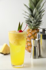 Tasty pineapple cocktail with cherry in glass on light table