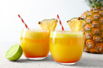 Tasty pineapple cocktail in glasses served on white table