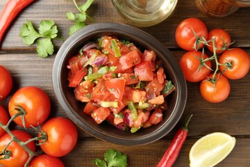 Delicious spicy salsa with ingredients on wooden table, flat lay