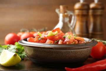 Delicious spicy salsa with ingredients on wooden table, closeup