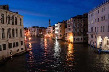 Night view of grand canal with boats, gondolas, mansions along. Venice, Italy.