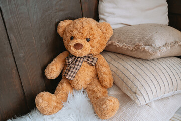 Cozy teddy bear sitting on soft pillows in a warm, inviting corner
