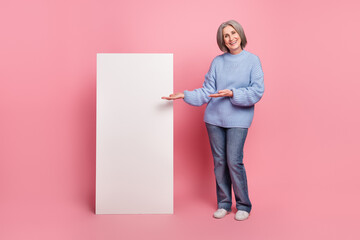 Full body size photo of promoter grandmother wearing blue knitted pullover direct hands huge phone screen new app isolated on pink color background