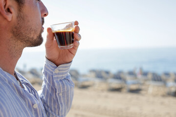 Drinking coffee on the beach. Attractive man enjoying the sea view from the beach bar on a sunny day reflecting on life.