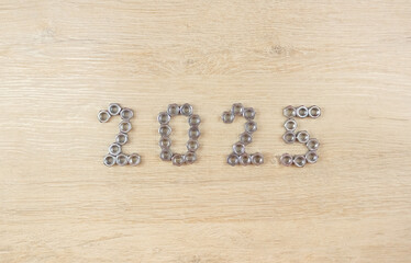 Number 2025 by metal nuts on a light wooden background. 2025 year