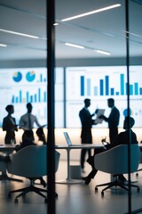 Blurred professionals collaborating on a planning session, large digital screens in the background displaying charts in modern office.