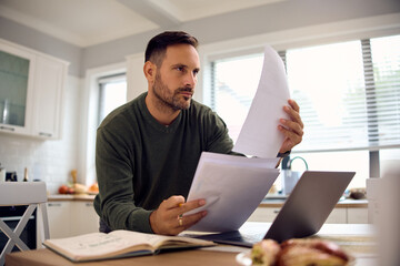 Male entrepreneur going through business reports while working at home.