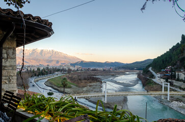 A panoramic view of Berat in Albania, with snow-capped mountains in the background. The image captures the serene beauty of a traditional settlement against a stunning natural