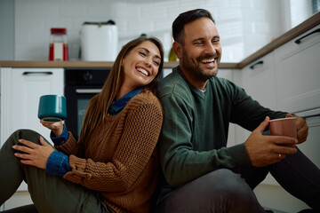 Carefree couple having a cup of tea while relaxing in their kitchen.