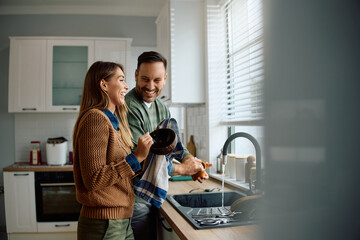 Happy couple having fun while doing  dishes together.