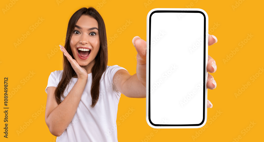 Poster wow, amazing useful app. portrait of excited and surprised young woman holding smartphone with black