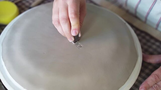Close-up of hand engraving identification numbers on a clay disk. 