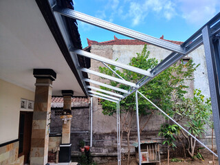 Construction of a lightweight steel canopy frame attached to a house. The frame is supported by...