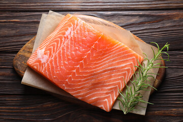 Piece of fresh salmon and rosemary on wooden table, top view