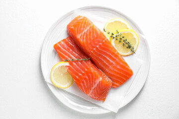 Pieces of fresh salmon with thyme and lemon on white table, top view